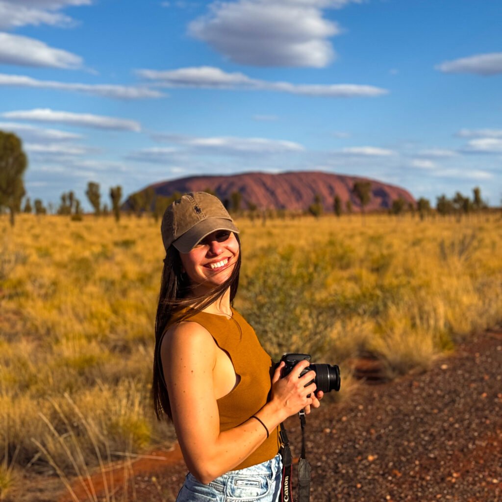 Lady smiling in front of Uluru or Ayers Rock in Northern Territory Australia with Camera